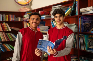 Enjoying reading school books, modern academies and schools, Arab Saudi Gulf students wearing school uniforms standing in the school library, doing homework, education in the Kingdom of Saudi Arabia.