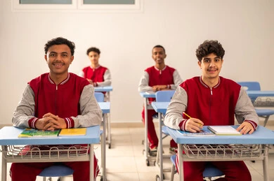 تعابير السعادة و السرور، الإستعداد للعام الدراسي الجديد، التعليم في السعودية، تأدية الواجبات المدرسية، العودة إلى المدارس، مجموعة من الطلاب العربيين الخليجيين السعوديين يرتدون الزي المدرسي يجلسون في مقاعدهم ويقومون بالاستماع الى الشرح