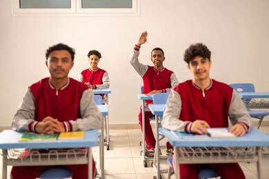 المشاركة الفعالة للتلاميذ، النشاط داخل الفصل الدراسي، مجموعه من الطلاب العربيون الخليجيون السعوديون يرتدون الزي المدرسي يجلسون داخل الفصل ، رفع اليد للاجابه على السؤال ، تطور طريقة التدريس في السعودية