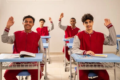 النشاط داخل الفصل الدراسي، مجموعه من الطلاب العربيون الخليجيون السعوديون يرتدون الزي المدرسي يرفعون ايديهم للإجابة عن السؤال، تطور طريقة التدريس في السعودية، المشاركة الفعالة للتلاميذ