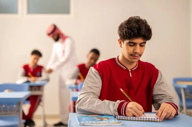 الإستعداد للعام الدراسي الجديد، التركيز أثناء حل أسئلة الامتحان، التعليم في المملكة العربية السعودية ، العودة إلى المدارس، مجموعه من الطلاب العربيين الخليجيين السعوديين يرتدون الزي المدرسي يجلسون في مقاعدهم برفقة معلمهم