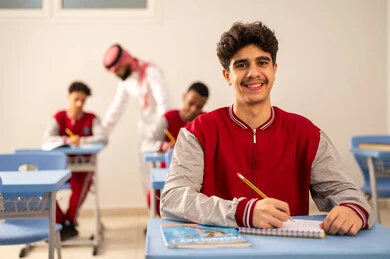التركيز أثناء حل أسئلة الامتحان، الإستعداد للعام الدراسي الجديد، التعليم في المملكة العربية السعودية ، العودة إلى المدارس، مجموعه من الطلاب العربيين الخليجيين السعوديين يرتدون الزي المدرسي يجلسون في مقاعدهم برفقة معلمهم