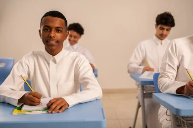 ايماءات التمعن والتركيز، أهداف التربية والتعليم، مجموعة من الطلاب العربيون الخليجيون السعوديون يرتدي الثوب الابيض يقومون بحل اسئلة الدرس، المشاركة الفعالة للطلاب، التعليم في المملكة العربيه السعودية