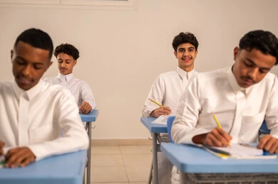 أهداف التربية والتعليم، مجموعة من الطلاب العربيون الخليجيون السعوديون يرتدي الثوب الابيض يقومون بحل اسئلة الدرس، ايماءات التمعن والتركيز، المشاركة الفعالة للطلاب، التعليم في المملكة العربيه السعودية