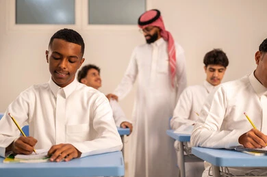 حوارات ودية بين الاستاذ والطلاب، المشاركة الفعالة للطلاب مع المدرسين، مجموعة من طلاب عربيين خليجيين سعوديين يرتدون الزي المدرسي يقومون بتأديه الواجبات ، جودة التعليم في السعودية، معلم عربي خليجي سعودي يرتدي الثوب التقليدي والشماغ يقوم بمناقشة الدروس مع طلابه، التربية والتعليم بالمناهج المقررة للتلاميذ