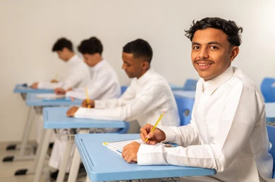 A group of Saudi Arabian Gulf Arab students wearing white thobes are sitting in their seats and doing their homework, completing school assignments, education in Saudi Arabia, preparing for the new school year, back to school.