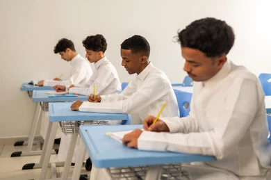 Education in Saudi Arabia, preparing for the new school year, returning to school, completing homework, a group of Arab Gulf Saudi students wearing white thobes sitting at their desks and doing their homework.