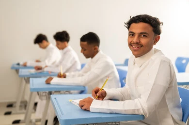 الإستعداد للعام الدراسي الجديد، العودة إلى المدارس، التعليم في السعودية، تأدية الواجبات المدرسية، مجموعة من الطلاب العربيين الخليجيين السعوديين يرتدون الثوب الابيض يجلسون في مقاعدهم ويقومون بحل الواجب