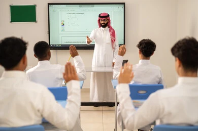 Expressions and gestures of excitement to know the correct answer, Arab Gulf students from Saudi Arabia wearing traditional attire raise their hands to answer, interaction and participation inside the classroom, education and teaching with the curricula prescribed for students in the Kingdom of Saudi Arabia. Expressions and gestures of excitement to know the correct answer, Arab Gulf students from Saudi Arabia wearing traditional attire raise their hands to answer, interaction and participation inside the classroom, education and teaching with the curricula prescribed for students in the Kingdom of Saudi Arabia.