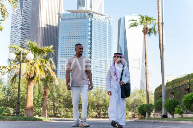 شابان عربيان خليجيان سعوديان يمارسان رياضة المشي في في إحدي منتزهات الرياض ، الاستجمام و التنزه في الهواء الطلق ، لقاء و تعارف ، مقابلة أصدقاء ، كامل الجسم ، صورة بالطول الكامل ، قضاء وقت ممتع في مدينة الملك عبد الله المالية ( كافد ) في مدينة الرياض ، الم