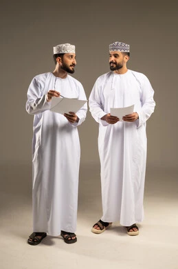 تقسيم و توزيع المهام، الوحده و العمل الجماعي، بورتريه لرجلين عربيين خليجيين عمانيين يرتديان الدشداشة و الكمة يحملان اوراق بيضاء, خلفية رمادية