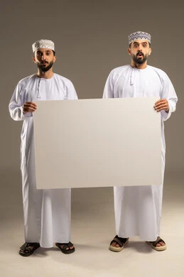 التفاجؤ من شيء ما، استعمال السبورة لتوضيح الاجراءات المتبعة, بورتريه لرجلين عربيين خليجيين عمانيين يرتديان الدشداشة و الكمة و ينظران الى الكاميرا بدهشة, خلفية رمادية