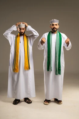 الفرح بالنصر و الفوز، إيماءات الحزن لخسارة الفريق، ارتداء الأوشحة التشجيعية, متابعة مباراة كرة القدم، بورتريه لرجلين عربيين خليجيين عمانيين يرتديان الدشداشة و الكمة تظهر عليهم تعابير التفاعل, خلفية رمادية