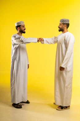 تلامش قبضتي اليدين, الصداقه و تكوين علاقات, بورتريه لرجلين عربيين خليجيين عمانيين يرتديان الدشداشة و الكمة و ينظران الى بعضهما بايماءات السعادة و السرور, خلفية صفراء