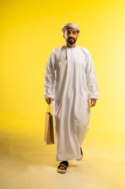 Buying products and items, shopping from commercial malls, taking advantage of seasonal offers and discounts, a portrait of an Arab Gulf Omani man wearing a dishdasha and a turban holding a paper bag in his hand, yellow background.