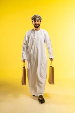 شراء المستلزمات و التبضع من المولات التجارية، الاستفادة من العروض الموسمية و التخفيضات، بورتريه لرجل عربي خليجي عماني يرتدي الدشداشة و العمامة يحمل بيده أكياس ورقية, خلفية صفراء