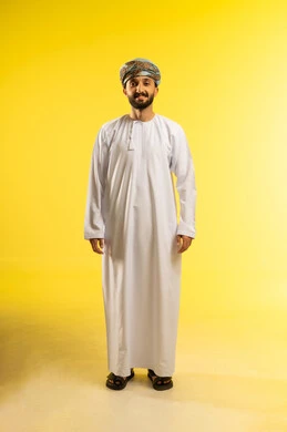 مفهوم الرجولة و القوة، الأناقة و الاهتمام بالمظهر الخارجي، بورتريه لرجل عربي خليجي عماني يرتدي الدشداشة و العمامة ينظر الى الكاميرا بايماءات السعادة و السرور, تعابير الثقة بالنفس، خلفية صفراء