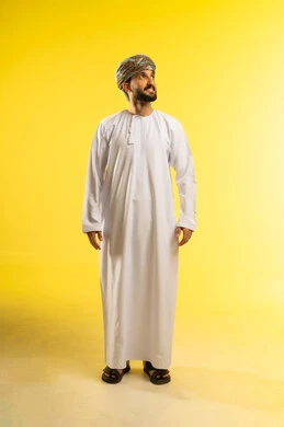 Elegance and attention to appearance, the concept of masculinity and strength, a portrait of an Arab Gulf Omani man wearing a dishdasha and a turban looking into the distance, gestures of happiness and joy, expressions of self-confidence, yellow background.