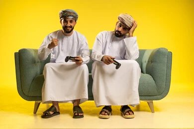 The concept of winning and losing, a portrait of two Arab Gulf men from Oman wearing the dishdasha and turban holding a game controller, the digital entertainment world, fun and entertainment with video games alongside friends, yellow background.