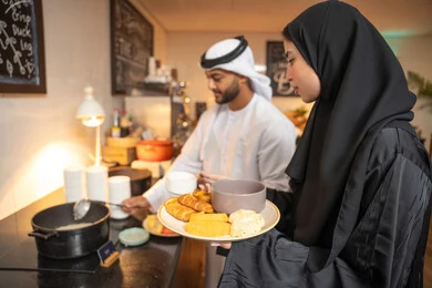 قضاء اوقات ممتعه في عطلة نهاية الاسبوع, اطباق متنوعه ومختلفه من المأكولات والمخبوزات الشهية والطارجة ،اختيار طبق الفطور ، زوجان عربيان اماراتيان  يرتديان الزي التقليدي الاماراتي يغرفان الطعام من البوفيه المفتوح في مطعم فاخر