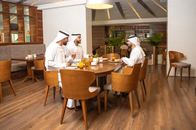 جلسة وناسة وتعارف، الاستمتاع بتناول الاطعمة اللذيذة, تبادل الأحاديث والاخبار, مشاركة الأصدقاء الأوقات الممتعة, بناء علاقات اجتماعية ناجحة, أصدقاء عرب خليجيون اماراتيون يرتدون الكندورة والغترة يجلسون في إحدى الكافيهات الفاخرة في المملكة