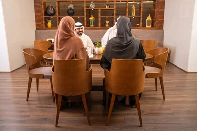 جلسة وناسة وتعارف، نقاشات و حوارات عائليه على مائدة الطعام, عائلة عربية اماراتية خليجيه يرتدون الزي التقليدي يجلسون في مطعم فاخر،  تناول وجبات طعام لذيذة، قضاء أوقات عائليه ممتعه في عطلة نهاية الاسبوع, صداقات وبناء علاقات اجتماعيه