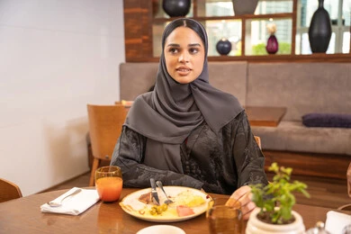 Enjoying outside the home, an Arab Gulf Emirati woman wearing an abaya and hijab sits in a luxurious restaurant, spending enjoyable times in one of the cafes in the UAE, exchanging conversations and dialogues, having breakfast, and engaging in recreational youth activities. Enjoying outside the home, an Arab Gulf Emirati woman wearing an abaya and hijab sits in a luxurious restaurant, spending enjoyable times in one of the cafes in the UAE, exchanging conversations and dialogues, having breakfast, and engaging in recreational youth activities.