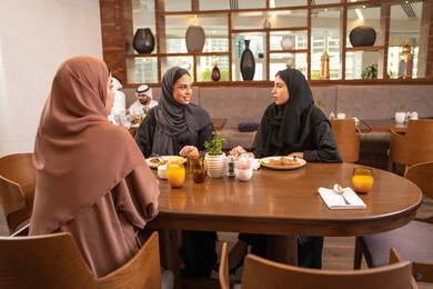 A fine restaurant in the UAE, delicious food and meals, having enjoyable conversations among friends, a fun and social gathering, Arab Gulf Emirati friends sitting in one of the luxurious restaurants enjoying their meal, building social relationships, a meeting on the weekend.