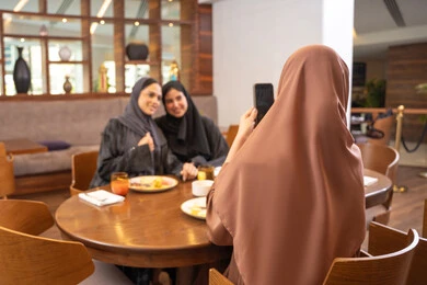 قضاء وقت ممتع بين الإصدقاء، التقاط الصور التذكارية باستخدام الهاتف المحمول، جلسة وناسة وتعارف، بناء علاقات إجتماعية، مطعم راقي في الامارات ، أطعمة ووجبات لذيذة، صديقات عربيات خليجيات اماراتيات يجلسن في إحدى المطاعم الفاخرة، اجتماع في عطلة نهاية الأسبوع