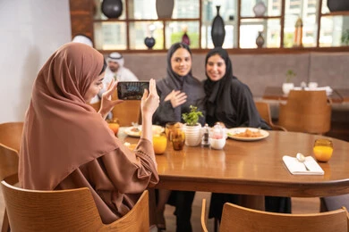 قضاء وقت ممتع بين الإصدقاء، التقاط الصور التذكارية باستخدام الهاتف المحمول، جلسة وناسة وتعارف، بناء علاقات إجتماعية، مطعم راقي في الامارات ، أطعمة ووجبات لذيذة، صديقات عربيات خليجيات اماراتيات يجلسن في إحدى المطاعم الفاخرة، اجتماع في عطلة نهاية الأسبوع