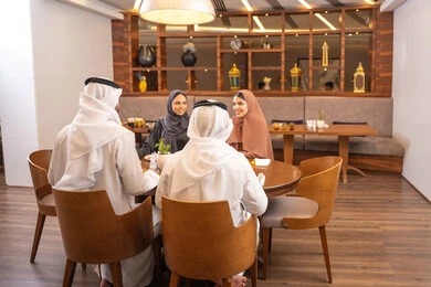 جلسة وناسة وتعارف، نقاشات و حوارات عائليه على مائدة الطعام, عائلة عربية اماراتية خليجيه يرتدون الزي التقليدي يجلسون في مطعم فاخر،  تناول وجبات طعام لذيذة، قضاء أوقات عائليه ممتعه في عطلة نهاية الاسبوع, صداقات وبناء علاقات اجتماعيه