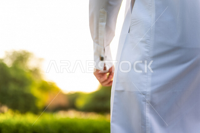 صورة مقربة ليد رجل عربي خليجي سعودي بخلفية من الطبيعة الخلابة في إحدى حدائق المملكة العربية السعودية ، يرتدي الزي التقليدي السعودي