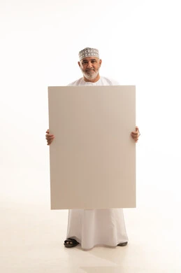 Marketing advertisements and promotions, gestures of joy and happiness, use of explanatory informational boards, white rectangular mockup, portrait of a smiling Omani Gulf Arab man wearing a dishdasha and kumma holding a large empty rectangular white board in his hand, full-body image, white background.