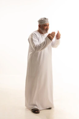 ايماءات التوسل والاسترحام، رفع اليدين للأعلى بهدف الدعاء والتضرع إلى الله تعالى، طلب المساعدة من المولى عز وجل، بورتريه لرجل عماني شايب يرتدي الدشداشة والكمه يدعي ويطلب المغفرة، ضم الكفين امام الصدر للقيام بالدعاء، الجسم بالطول الكامل، خلفية بيضاء