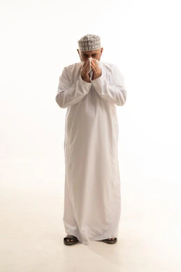 الإصابة بالزكام والانفلونزا، العطاس والكحه وأعراض الرشح، بورتريه لرجل شايب عربي خليجي عماني يرتدي الدشداشة والكمه العمانية يمسك المنديل الورقي بيده لمنع انتشار العدوى، الإرهاق والتعب والحاجة للراحة، ضرورة أخذ العلاج المناسب، الجسم بالطول الكامل، خلفية بيضاء
