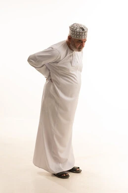 الشعور في الالم بالعمود الفقري ,بورتريه لرجل عربي خليجي عماني يرتدي الدشداشة والكمة يشعر بوجع في أسفل الظهر, أمراض المفاصل والعضلات, التعب والإرهاق و الحاجه للعلاج, طلب المساعده للذهاب الى الطبيب, الجسم بالطول الكامل, خلفية بيضاء