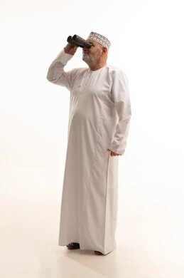 التخطيط المستقبلي للأهداف و الطموحات، رؤية الاشياء البعيدة و تقريبها, ايماءات الاستمتاع و السرور,  بورتريه من الجانب لرجل عربي خليجي عماني يرتدي الدشداشة و الكمه مبتسم يحمل بيده منظار ثنائي العينين و يينظر الى شيئ ما, صورة الجسم بالطول الكامل, خلفية بيضاء