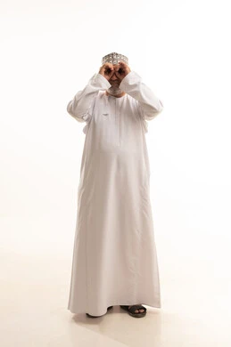 Love of exploration and adventure, seeing distant things and bringing them closer, gestures of enjoyment and joy, a portrait of a young Arab Gulf Omani man wearing a dishdasha and a kumma, smiling while holding a binocular in his hand and looking at something, full-body image, white background.