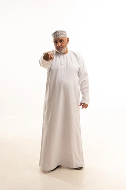 توجيه أصابع الاتهام إلى شخص ما، بورتريه لرجل كبير بالسن عربي خليجي عماني يرتدي الدشداشة والكمه يشير باصبع السبابة نحو الكاميرا بشكل مباشر بإيماءات الجدية والغضب، الإشارة إلى مكان ما محدد، الجسم بالطول الكامل، خلفية بيضاء