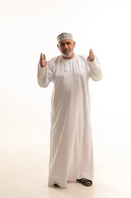 Requesting help from the Almighty, gestures of intercession and supplication, raising hands upwards for the purpose of praying and beseeching God Almighty, a portrait of an elderly Omani man wearing a dishdasha and kumma, praying and asking for forgiveness, hands clasped in front of the chest for the act of prayer, full-body, white background.