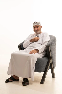 التشخيص السريع والرعاية المنزلية، متابعة دورية للحالة الصحية العامة، بورتريه مقرب لشايب عربي خليجي عماني يرتدي الدشداشة والكمه يستخدم السماعة الطبية ليقوم بفحص نفسه  يجلس على الكرسي، العمل في القطاع الصحي ، خلفية بيضاء