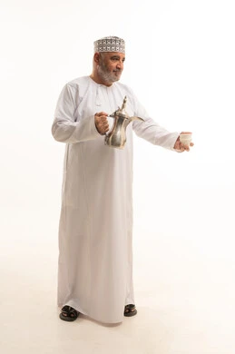 A local national product, honoring the guest and good hospitality and reception, a portrait of an elderly Arab Omani Gulf man wearing traditional attire holding an Arabic coffee pot in his hand, gestures of warmth and welcoming guests, happy Islamic holidays and occasions, full body length, white background.