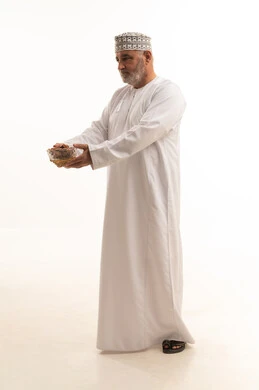 Delicious Ramadan hospitality, a local national product and crop, a meal with high nutritional value, a portrait of an Arab Gulf Omani man wearing traditional attire holding a plate of healthy dates, the iftar of the fasting person in Ramadan, celebrating the arrival of the month of goodness, full-body shot, white background.