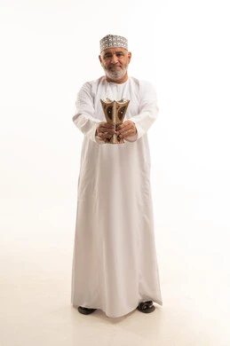 مفهوم التطيب بالبخور, استخدام خشب العود بالأعياد والمناسبات, العادات والتقاليد العربية, بورتريه لرجل كبير مسن عربي خليجي عماني يرتدي الزي التقليدي يقوم بالتعطر من المبخرة, الاهتمام بالمظهر الخارجي والأناقة، الجسم بالطول الكامل، خلفية بيضاء