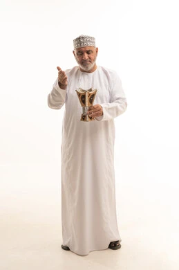 استخدام خشب العود بالأعياد والمناسبات, مفهوم التطيب بالبخور, العادات والتقاليد السعودية, بورتريه لرجل كبير مسن عربي خليجي عماني يرتدي الزي التقليدي يقوم بالتعطر من المبخرة, الاهتمام بالمظهر الخارجي والأناقة، الجسم بالطول الكامل، خلفية بيضاء