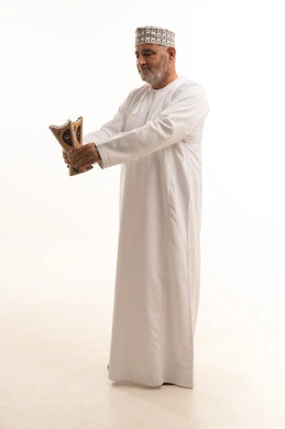 استخدام خشب العود بالأعياد والمناسبات, مفهوم التطيب بالبخور, العادات والتقاليد السعودية, بورتريه لرجل كبير مسن عربي خليجي عماني يرتدي الزي التقليدي يقوم بالتعطر من المبخرة, الاهتمام بالمظهر الخارجي والأناقة، الجسم بالطول الكامل، خلفية بيضاء