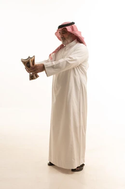 The use of oud wood during holidays and occasions, the concept of perfuming with incense, Saudi customs and traditions, a portrait of an elderly Arab Gulf Saudi man wearing traditional attire and a ghutrah, applying perfume from a incense burner, attention to external appearance and elegance, full-body, white background.