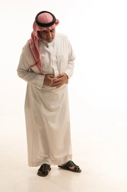 عسر الهضم والشعور بحرقة في المعدة، الحاجة للدواء ووضع خطة علاجية, الإحساس بالمغص و التعب والإرهاق, بورتريه لرجل مسن عربي خليجي سعودي يرتدي الثوب التقليدي والشماغ يمسك بطنه بإيماءات الألم،  طلب المساعده للذهاب الى الطبيب، صورة الجسم بالطول الكامل، خلفية بيضاء