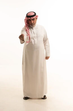 مفهوم الاناقة والاهتمام بالمظهر الخارجي، بورتريه لرجل عربي خليجي سعودي مسن يرتدي الثوب والشماغ التقليدي، الاشارة بإيماءات التمهل والانتظار، الجسم بالطول الكامل، خلفية بيضاء