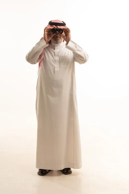 رؤية الاشياء البعيدة، الأناقة والوسامة والاهتمام بالمظهر الخارجي، بورتريه لرجل عربي خليجي سعودي كبير السن يرتدي الزي التقليدي يحمل بيده منظار ثنائي العينين، الجسم بالطول الكامل، خلفية بيضاء